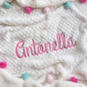 Cobija beige con pompones de colores